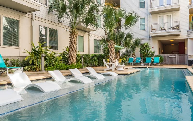 a pool with chairs and trees by it